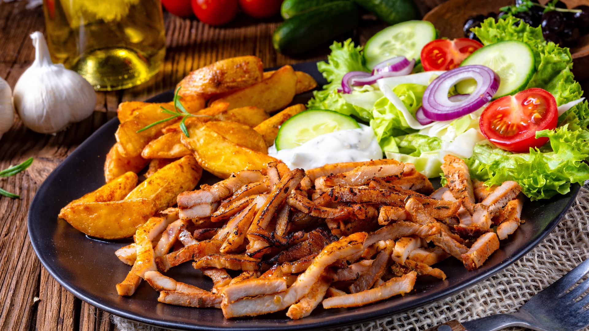 Rustikaler Gyros-Teller mit grünem Salat und Kartoffelecken